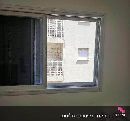 חלון אלומיניום עם מסגרת כסופה על קיר לבן